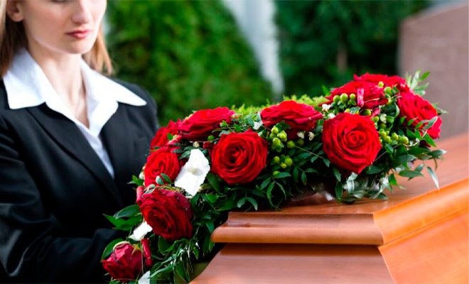 Ataúd con ramo de flores rojas y mujer al lado