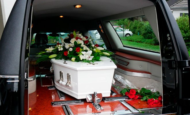Ataúd blanco con flores dentro de coche funebre